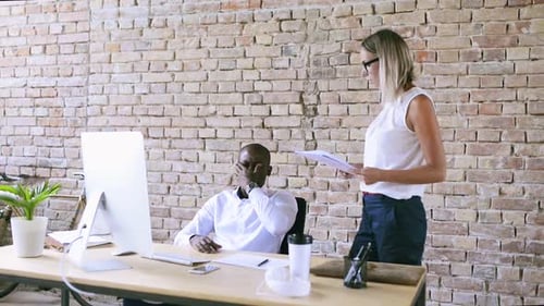 Young businesswoman and businessman collaborating on a project in modern office