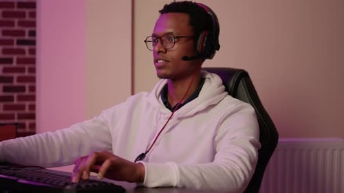 Young Adult Playing Computer Game With Headset