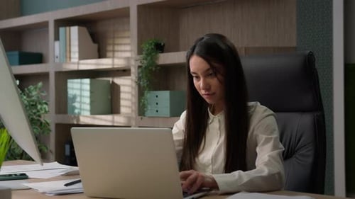 Woman Working on Laptop in Professional Office Setting