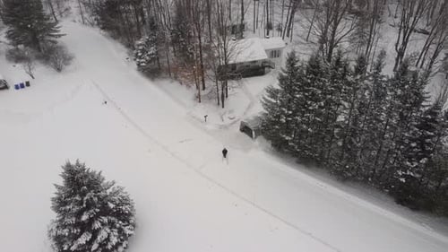 Man clears snowy path to remote lodge in peaceful winter paradise