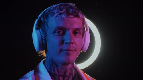 Smiling Young Adult with Headphones in Neon Lighting