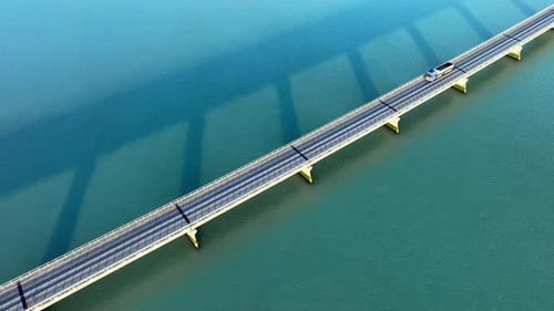 Brücke über türkisfarbenem Wasser: Drohnenaufnahme eines Autos, das auf einer Brücke fährt, beeindruckend, städtisch