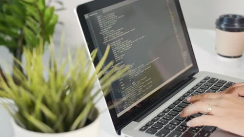 Mujer programadora escribiendo código HTML de un programa sentada en el lugar de trabajo en la oficina