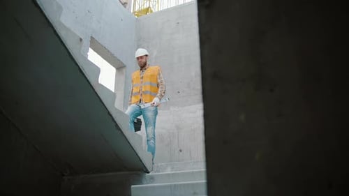 Construction Worker Walks Down Stairs in Building