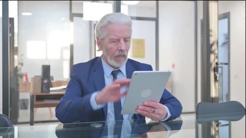 Senior Businessman Shocked by Tablet News in Office