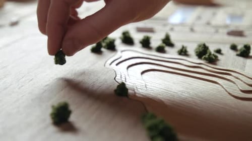 Person creates miniature town from ecological material on wooden table
