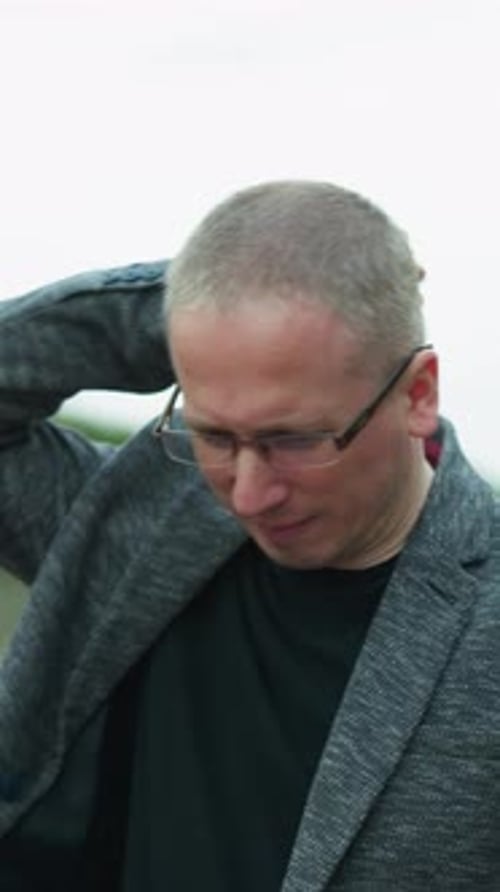 Gray Haired Man Scratching Head in Nature