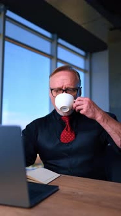 Busy Caucasian male sitting at the desk in the office in front of his laptop.