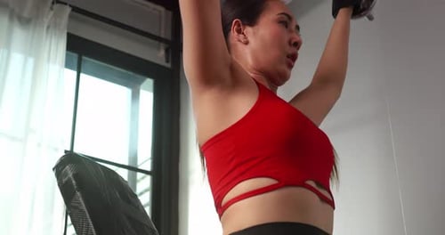 Strong Woman Doing Dumbbell Presses in Home Gym