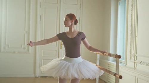 Elegant Ballerina Practices at Barre in Bright Studio