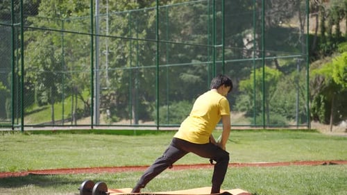 Young Man Stretching on Yoga Mat in Park