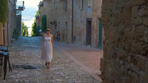 Woman Exploring a Cobblestone Alley in a Medieval Italian Town