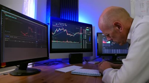 A city trader in a crypto and forex stock trading office. The mature man is taking notes.