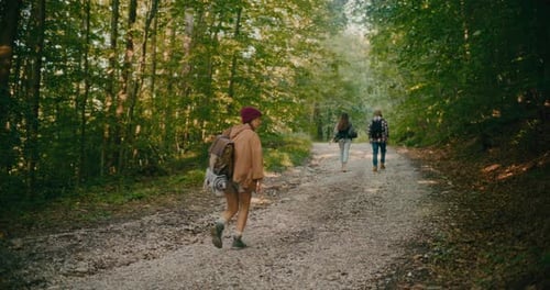 Young Woman Walking On Footpath With Friends In Forest