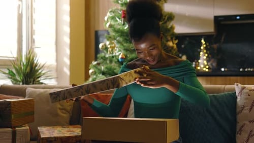 Excited Woman Opening Christmas Present at Home