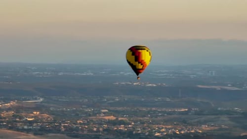 Hot Air Balloon Flying Over City at Sunrise