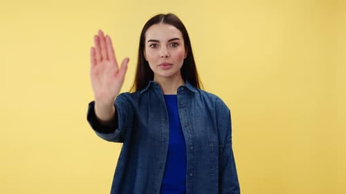 Woman Gesturing Stop with Hand in Front of Yellow