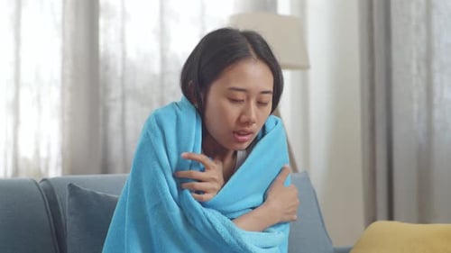 Gros plan d'une femme asiatique malade avec une couverture ayant froid sur le canapé dans le salon à la maison