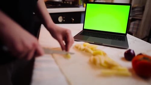 Woman cutting vegetables and searching for a recipe on her laptop with chroma key