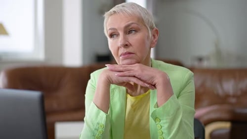 Thoughtful Woman with Hands Clasped at Desk
