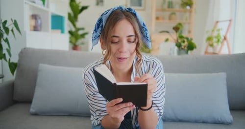 Smiling Woman Writing in a Journal on Couch