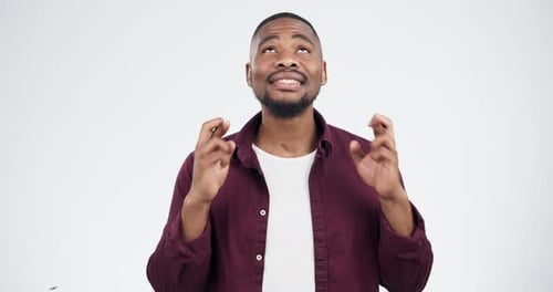 Face, fingers crossed black man in studio for hope, luck or wish, nervous