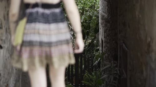 Caucasian Girl Goes Down the Stairs of a Stone Tunnel in Rack Focus View