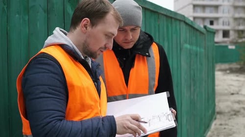Los ingenieros de construcción del sitio de construcción están discutiendo el proyecto de un edificio de gran altura.