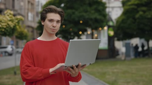 Handsome Caucasian Man Standing on the Street Utilizing a Laptop A Male Professional Working