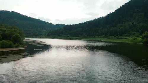 Aerial Drone Shot of Dramatic Natural Environment with Peaceful Lake Mysterious Bushy Green Woods