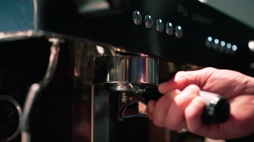 close-up of a barista's hand pressing freshly ground coffee before preparing it in a coffee machine