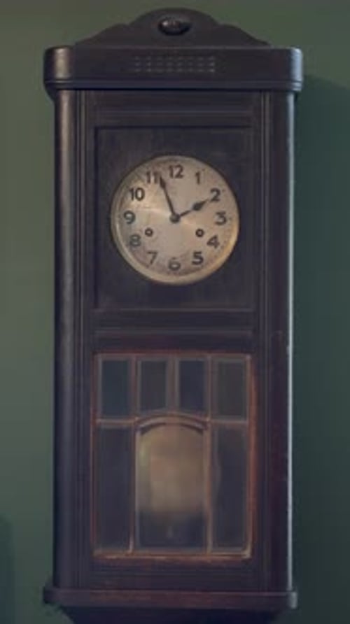 Antique Clock on Wall with Pendulum Swinging
