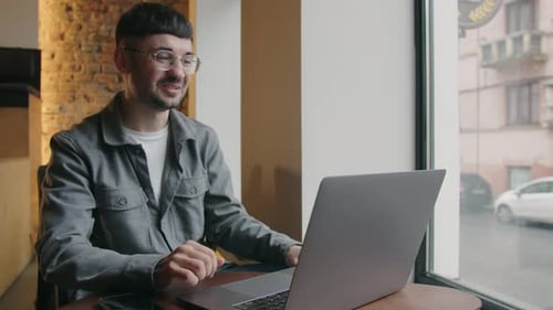 Young Adult Working on Laptop in Cafe