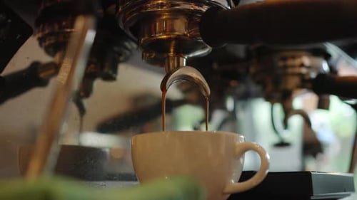 4K Close up of coffee maker machine pouring espresso shot into coffee cup.