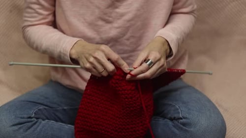 Woman Knitting a Red Scarf at Home