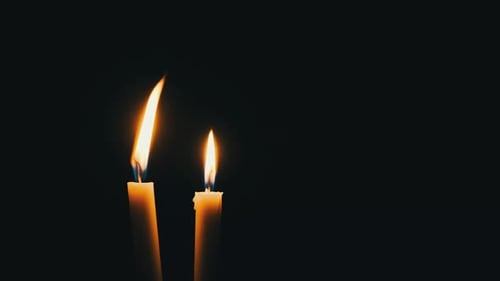 Two Candles are Lit on a Black Background Closeup