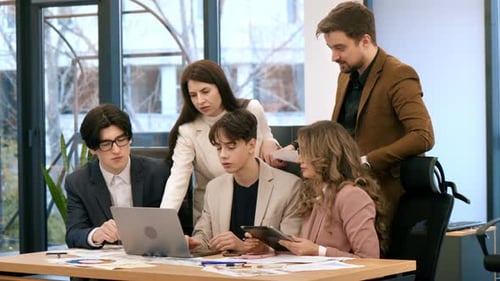 Business meeting in an office, workers discussing business affairs using laptop. Papers with charts