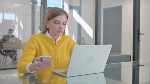 Woman Works at Laptop and Uses Smartphone