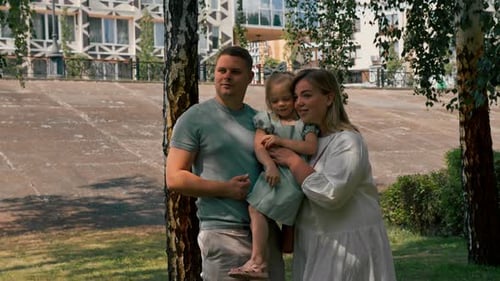Portrait of a smiling young family mom dad and little daughter family on a walk in the park happy