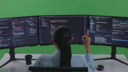 Asian Woman Thinking While Write Code With Multiple Computer Screens In Green Screen