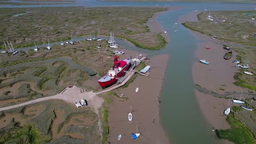 Circling aerial view above landmark Tollesbury lightship boat docked on Essex marina estuary