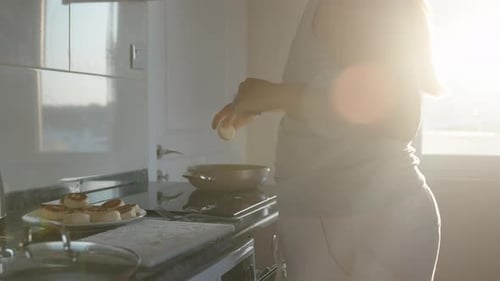 Cooking. I roll the cheese pancakes into flour and put them in a frying pan. Black countertop. White