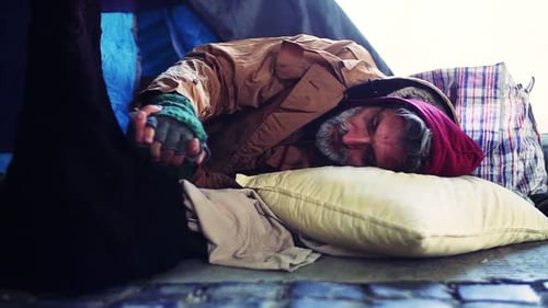 Homeless Beggar Man Lying Outdoors in a Tent in City