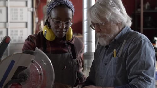 Man and Woman Cutting Wood in Workshop Together