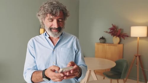 Mature Man Using Smartphone Indoors at Home