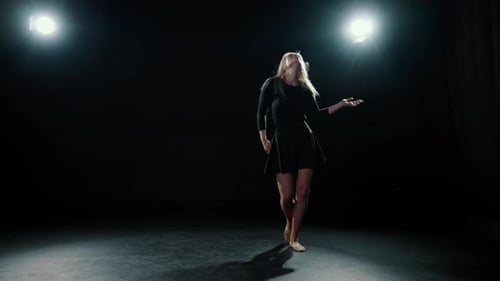 Graceful Woman Dancing Under Spotlight in Dark Studio