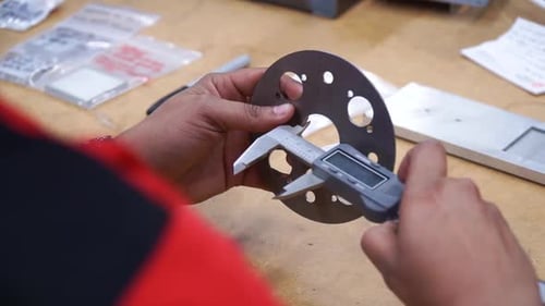 Female manufacturing engineer using caliper to measure material, close up