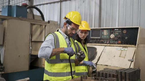 Blue collar workers are working at machine shop with CNC lathe machine.