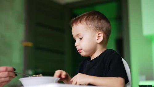 Cute Child Eating Breakfast in Highchair