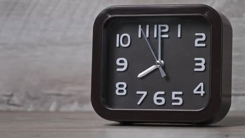El reloj puntero de forma cuadrada sobre mesa de madera muestra la hora 8 horas